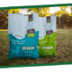 Several colorful bags of garden soil on a grassy lawn with trees in the background.